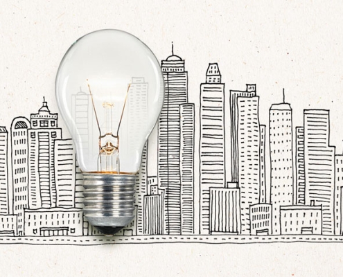 Picture of a real illuminated lightbulb laid over an illustrated cityscape