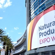 A picture of blue skies, palm trees and the Expo West sign on the outside of a building